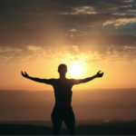 person with arms outstretched against sunset backdrop