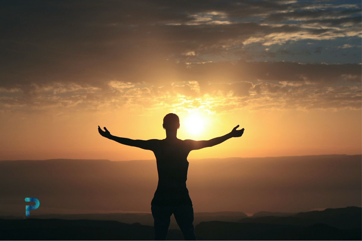 person with arms outstretched against sunset backdrop